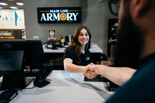 A Main Line Armory employee greeting a customer with a handshake.